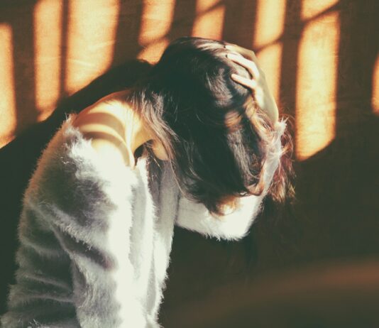 만성피로, 단순한 피로 아냐…지속되면 질병 신호일 수 있다 woman leans on wall in white fur jacket docking her head while holding it using her leaf hand