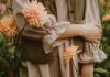 집에서도 실천 가능한 ‘마음 챙김’ 루틴, 스트레스 시대의 건강 관리법 A person in a brown gingham dress and corduroy vest among peach dahlias